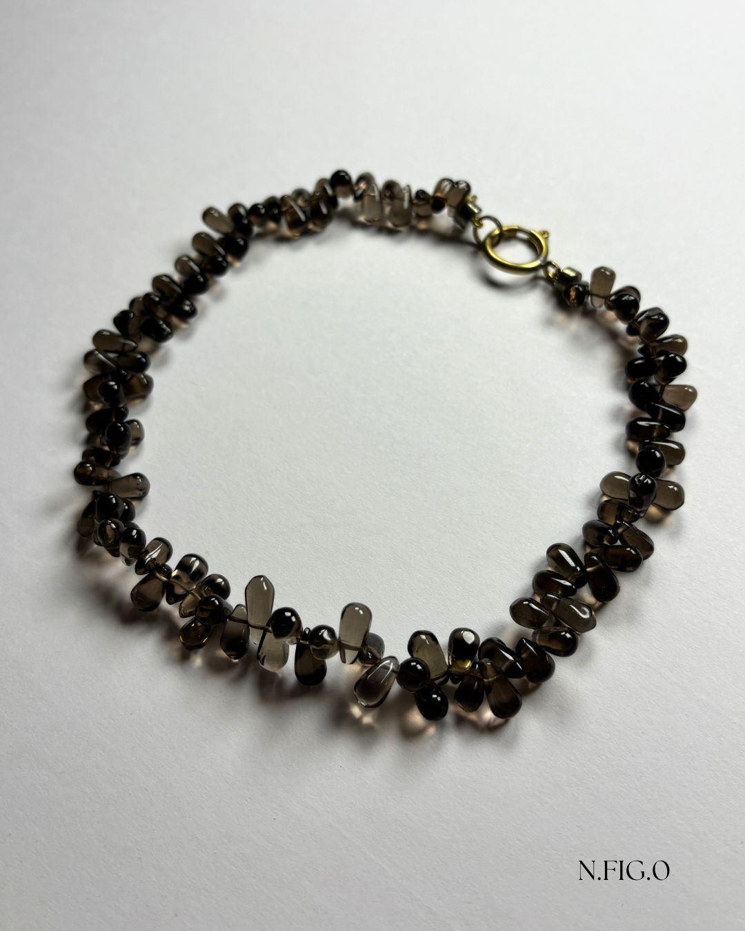 Close-up of smoky quartz gemstone drop beads strung in organic formation.
