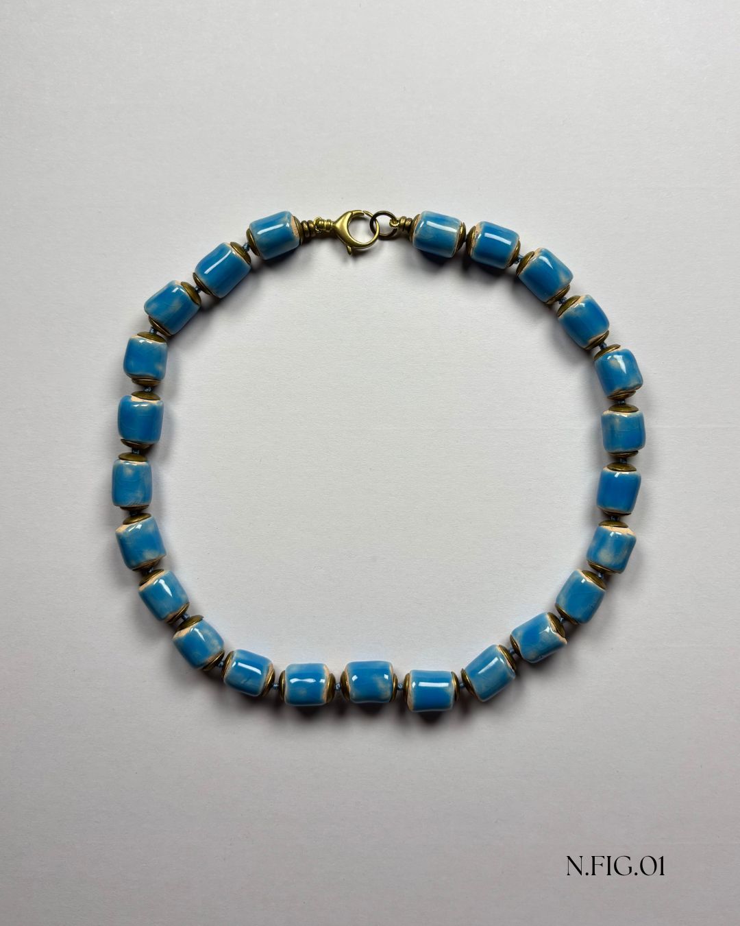 Handmade necklace featuring blue Czech glass barrel beads with picasso finish on white background.