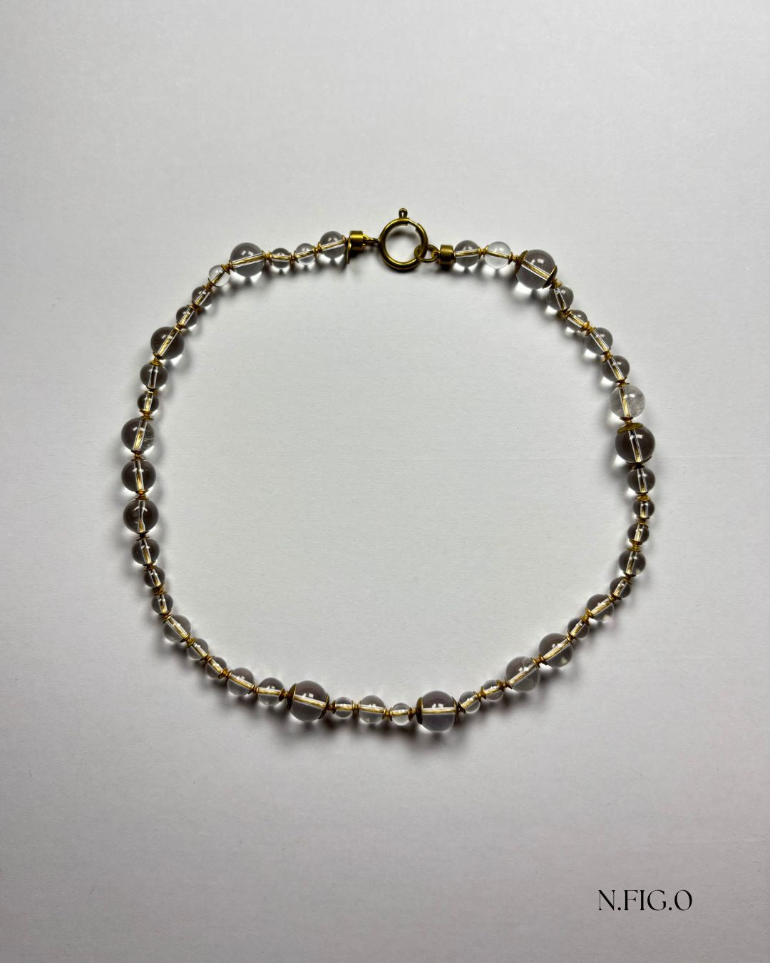 Handmade rock crystal necklace with polished clear quartz beads on white background.